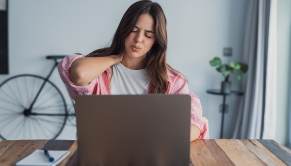 Woman experiencing neck pain at home desk