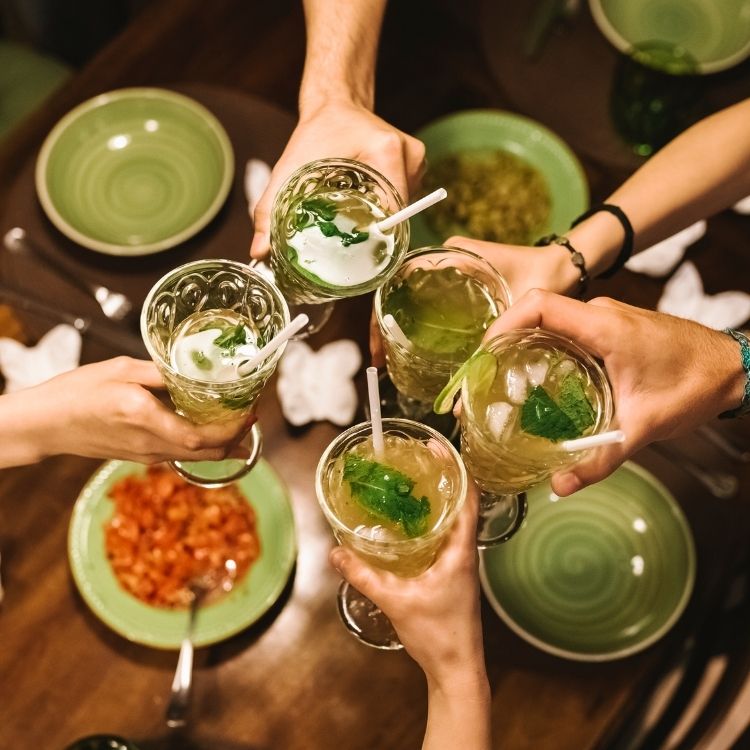 Group of friends toasting with mint garnished mocktails around a table